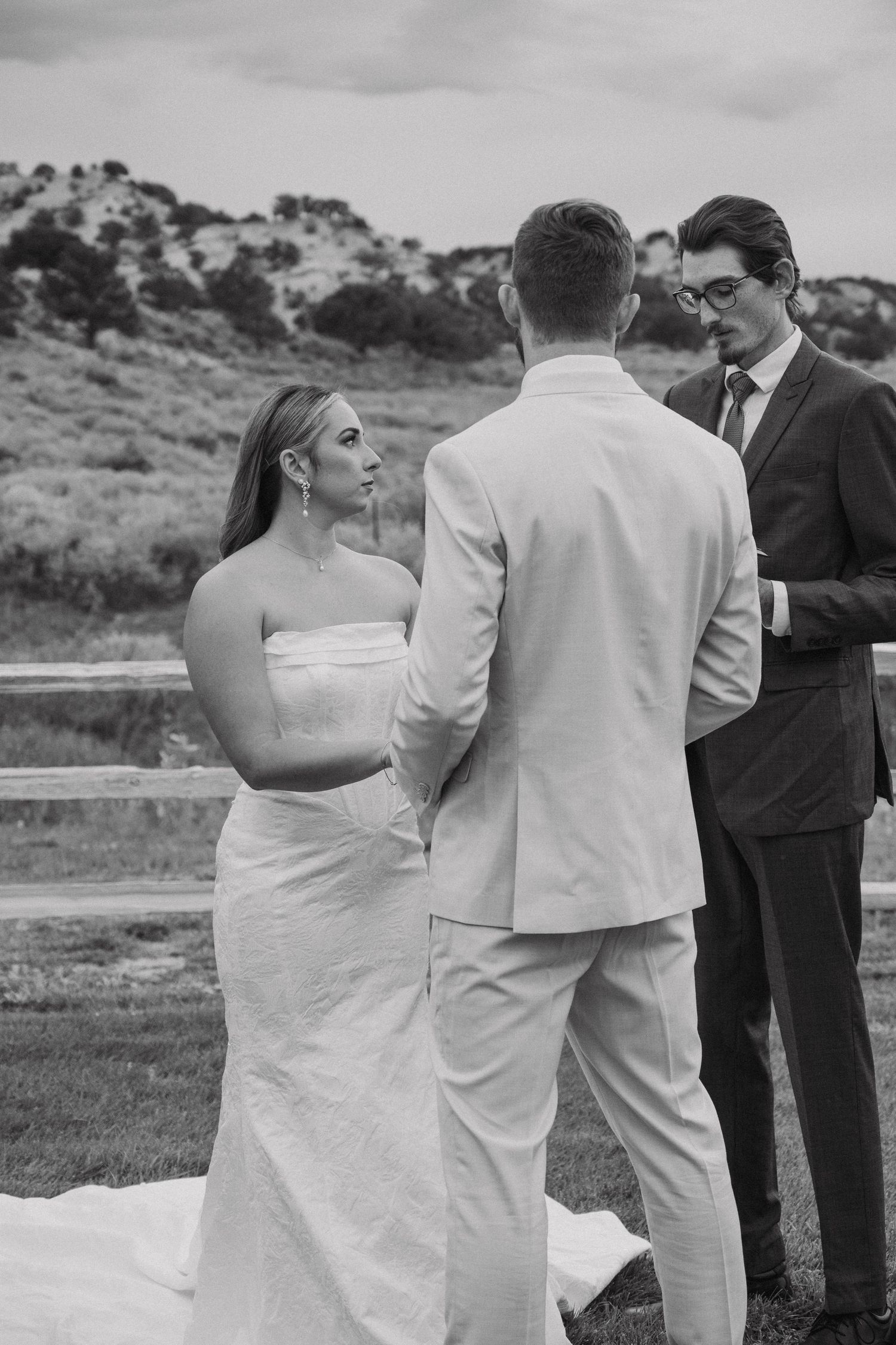 Black and white photo of a wedding ceremony in progress with attendants standing outdoors.