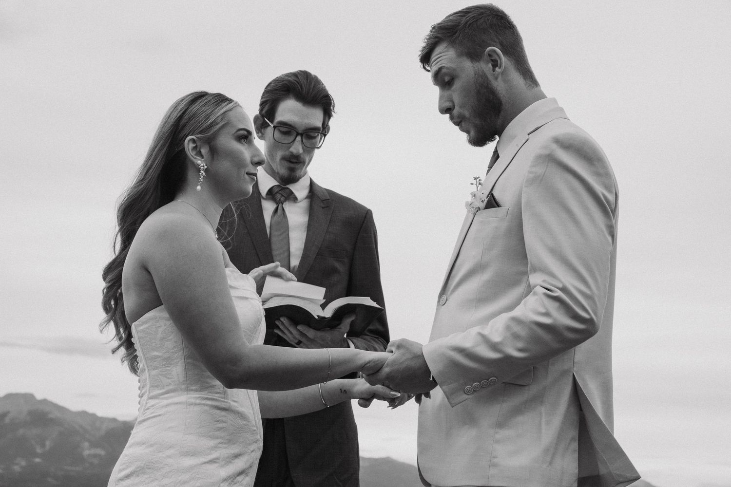 Black and white ceremony photos showing exchange of rings during wedding.