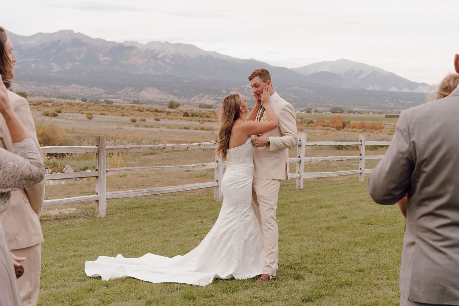 Wedding photoshoot in rustic outdoor setting with mountains and white fencing.
