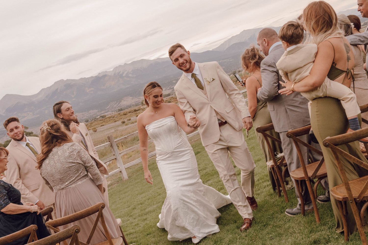Wedding party celebrating outdoors with mountains in the background.