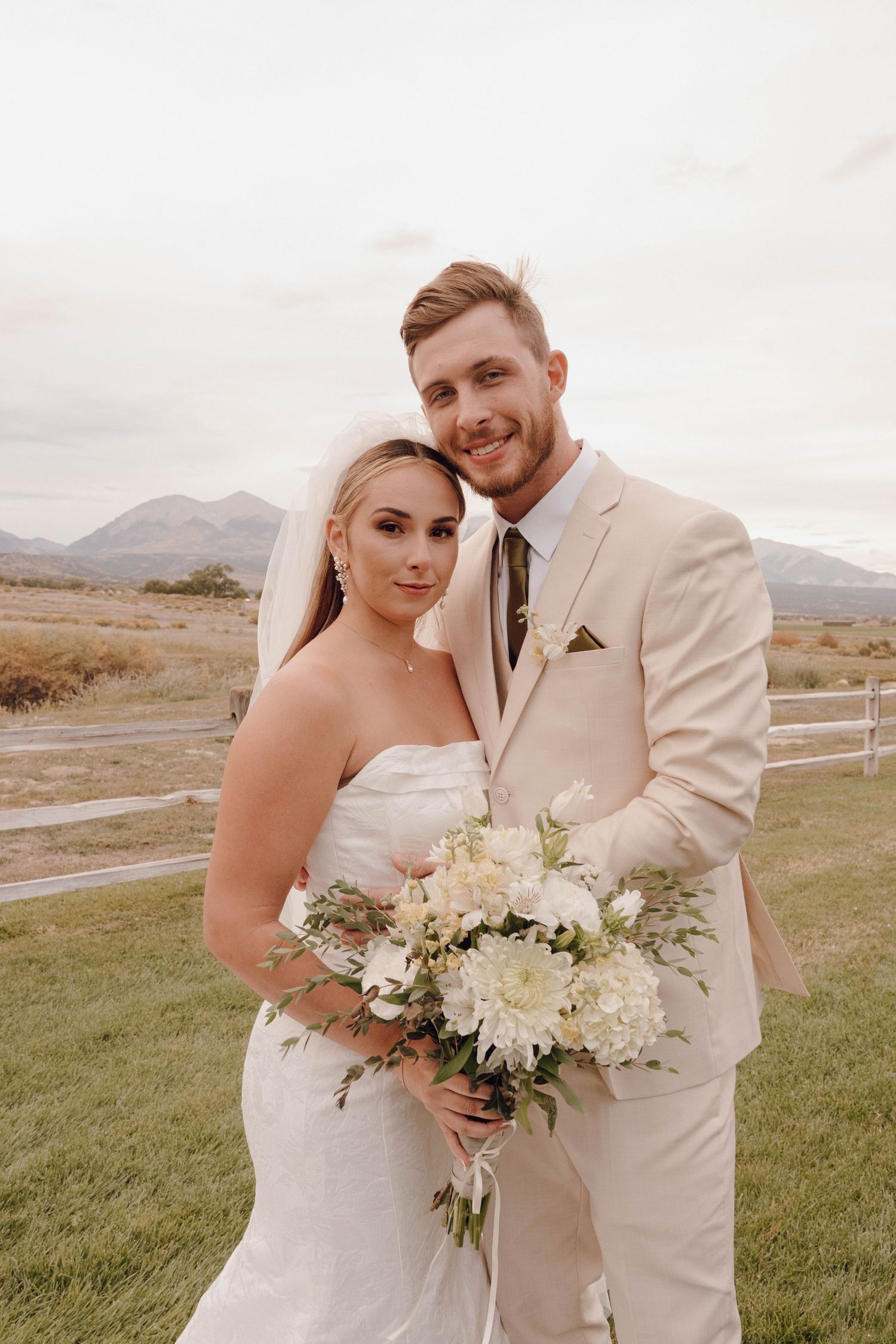 A romantic wedding photo series showing a couple in white and beige attire posing against a mountain landscape.