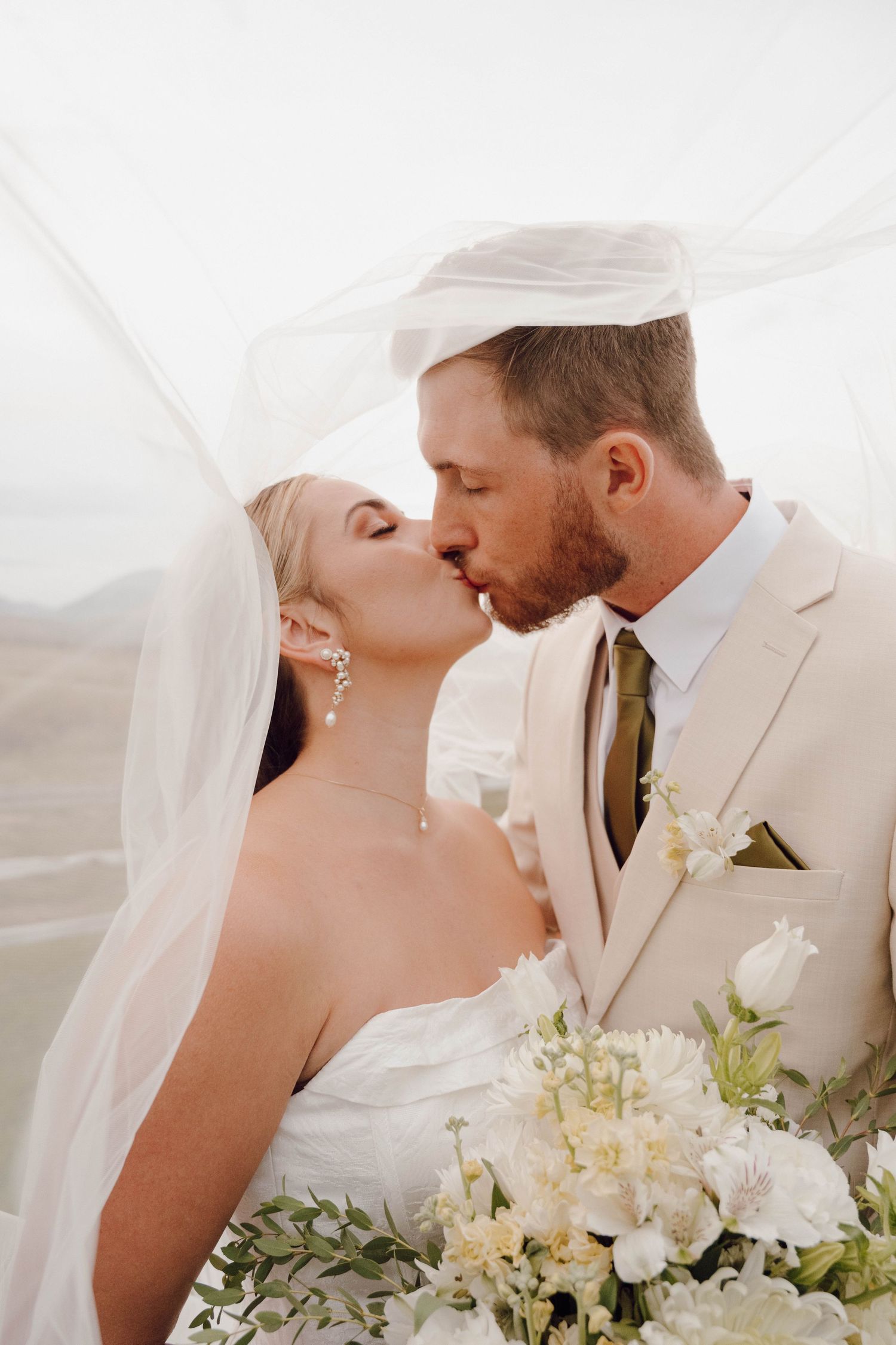 Close-up wedding photos of tender moments between newlyweds with white floral bouquet.
