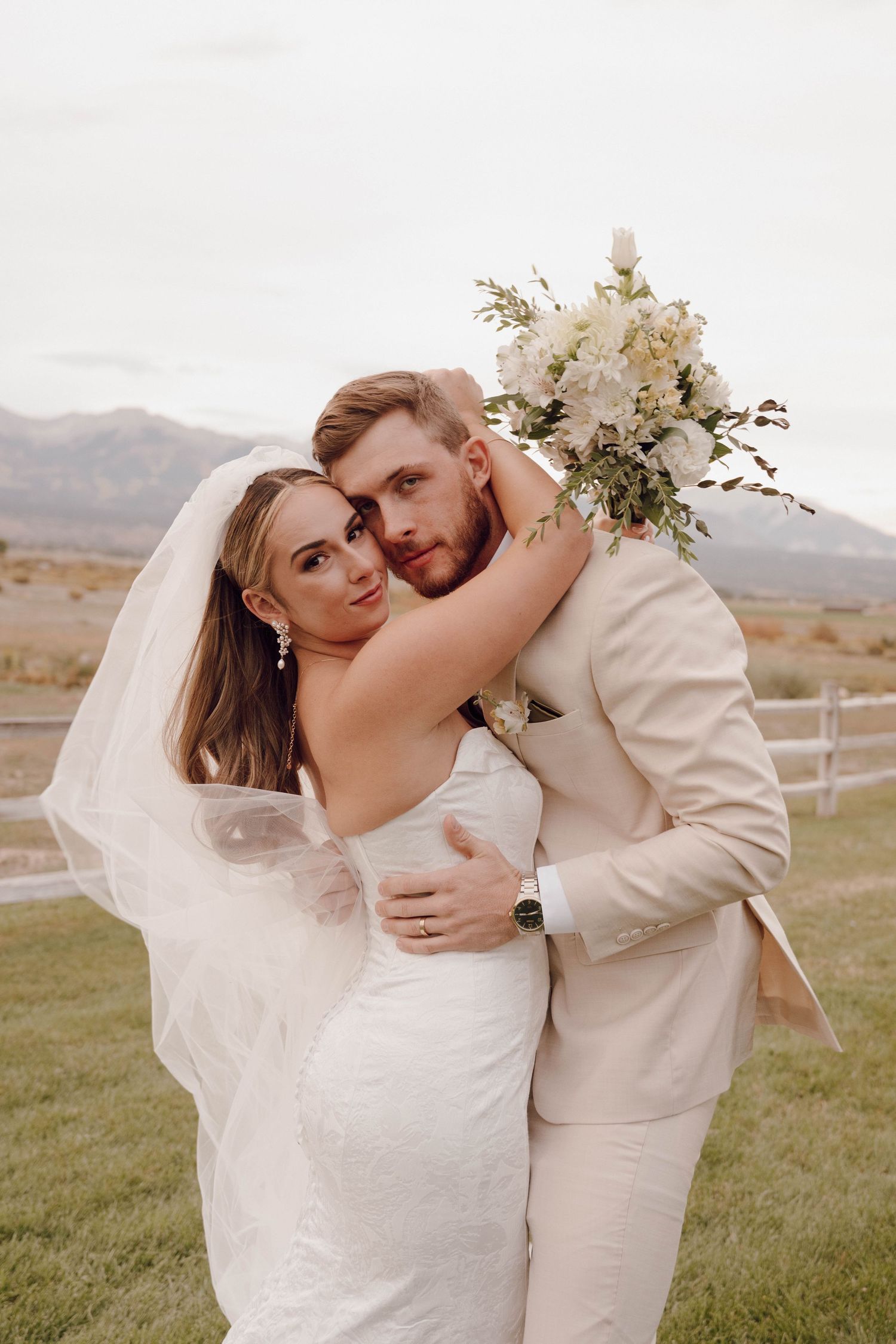 Newlyweds share tender moments in an outdoor wedding photoshoot with scenic mountain views.