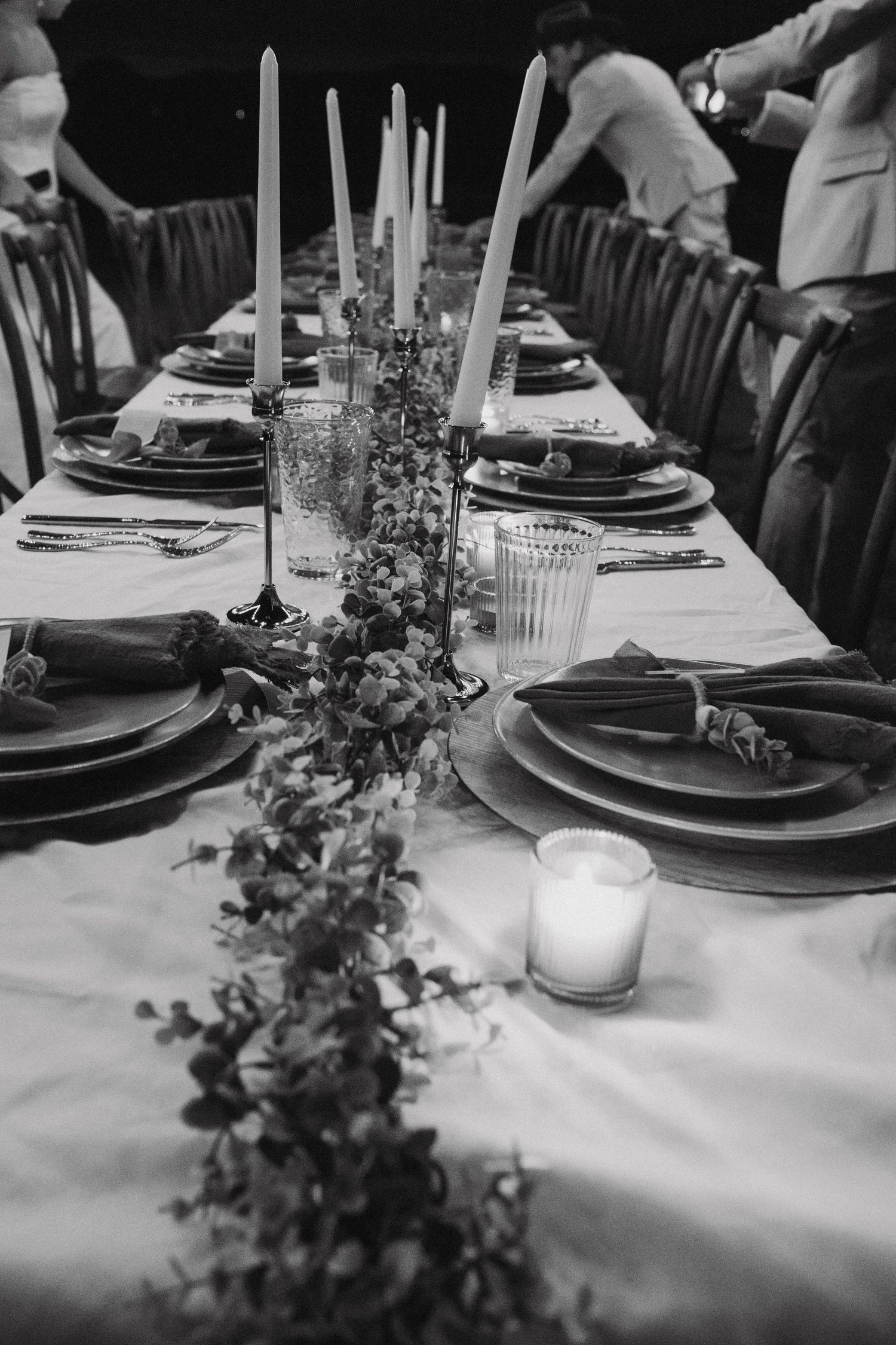 Elegant black and white table settings with candles and floral centerpieces at a formal wedding reception.