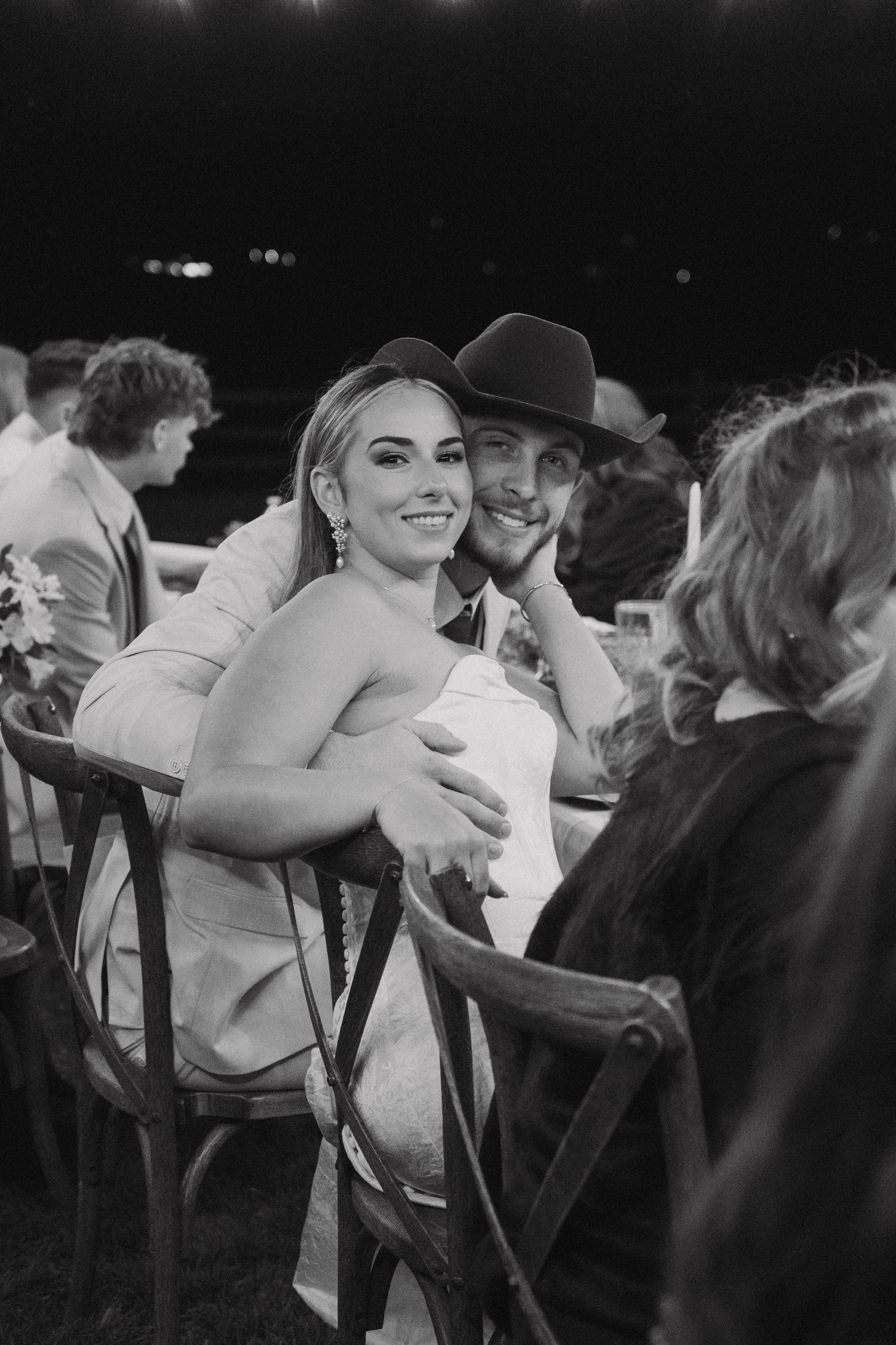 Wedding reception candid moments captured in black and white under string lights.