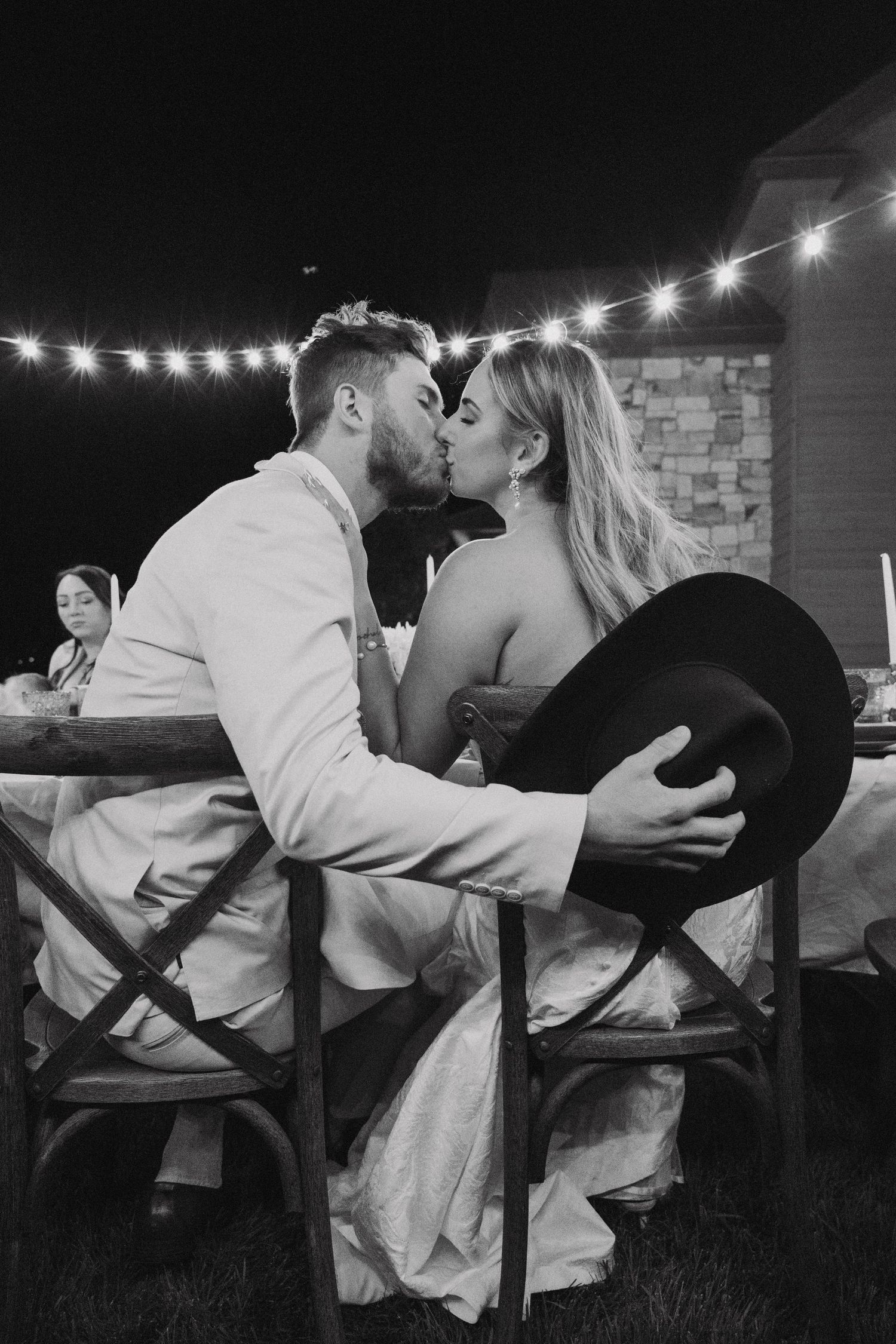 A romantic black and white photo series of a couple sharing a dance dip kiss under string lights.