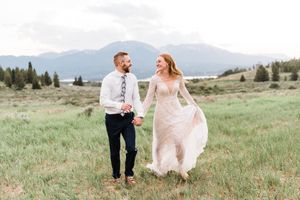 bride and groom running through open field in Breckinridge, CO