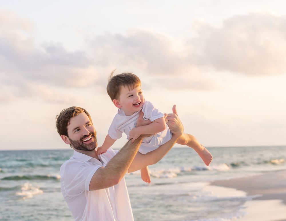Playful beach scene at sunset with people wearing coordinated white and khaki outfits enjoying the ocean breeze.