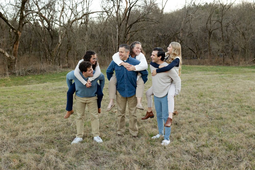 A group of people in casual clothing practicing yoga poses together in a grassy outdoor field.