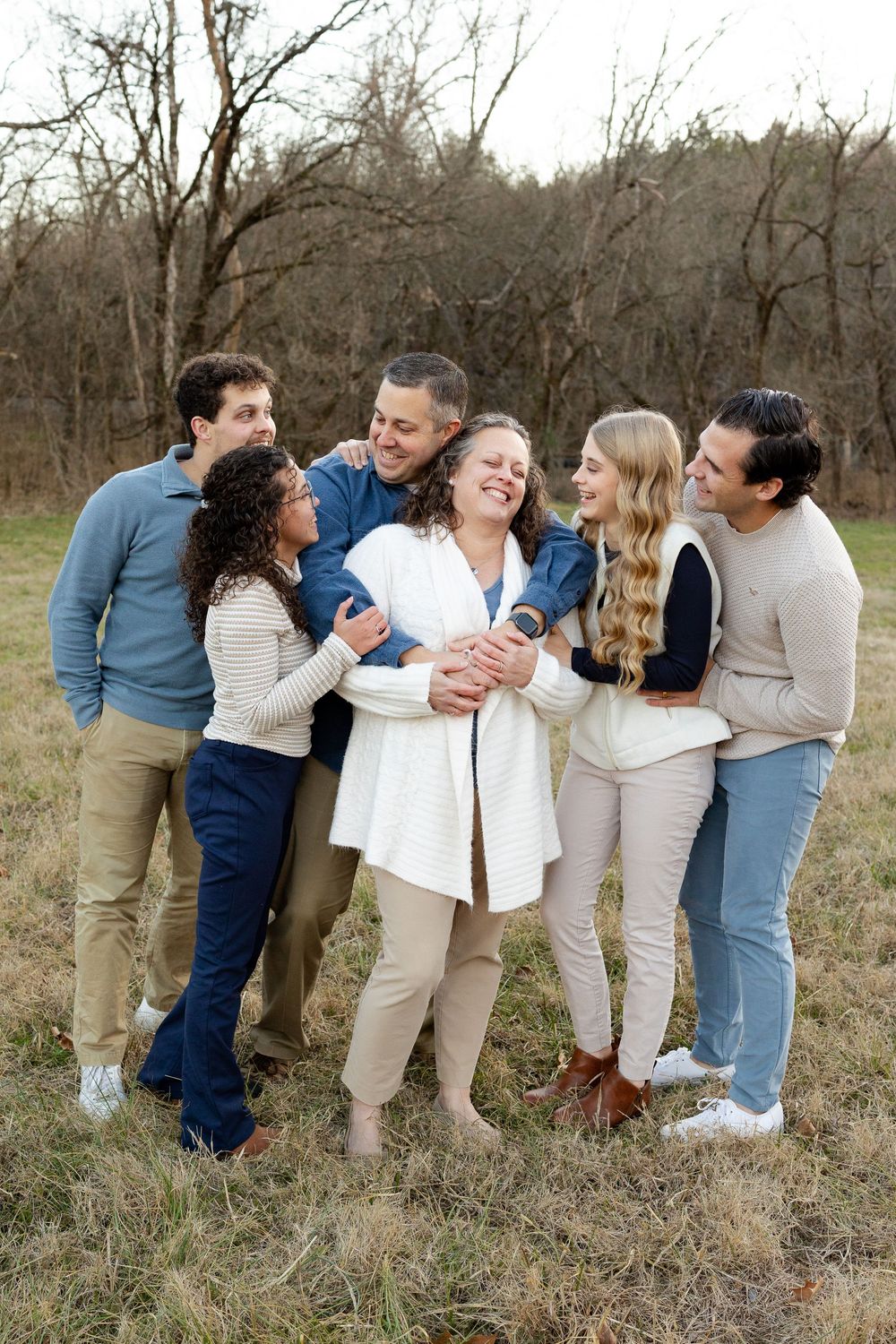 A group in coordinated casual outfits of denim and neutrals poses together in a natural outdoor setting.