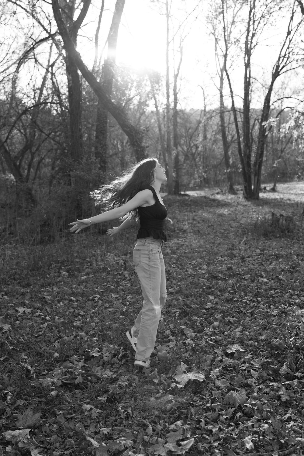 A sequence of black and white photos showing someone performing a cartwheel motion in a wooded area covered in fallen leaves.