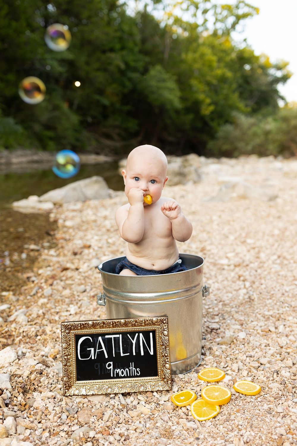 A series of milestone photos showing a baby in a metal tub with bubbles and rubber ducks on a rocky beach setting.