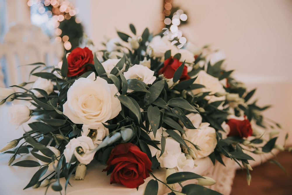 A series of floral arrangements featuring red roses and white flowers with lush greenery for a wedding celebration.