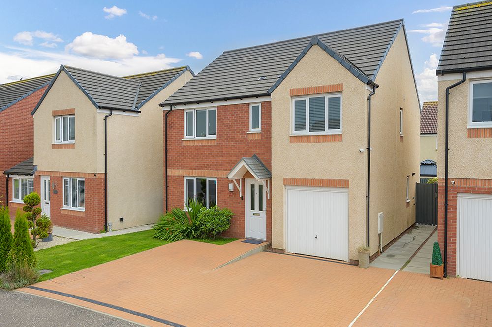 Modern residential development showing multiple brick and stone homes with garages and driveways on a sunny day.