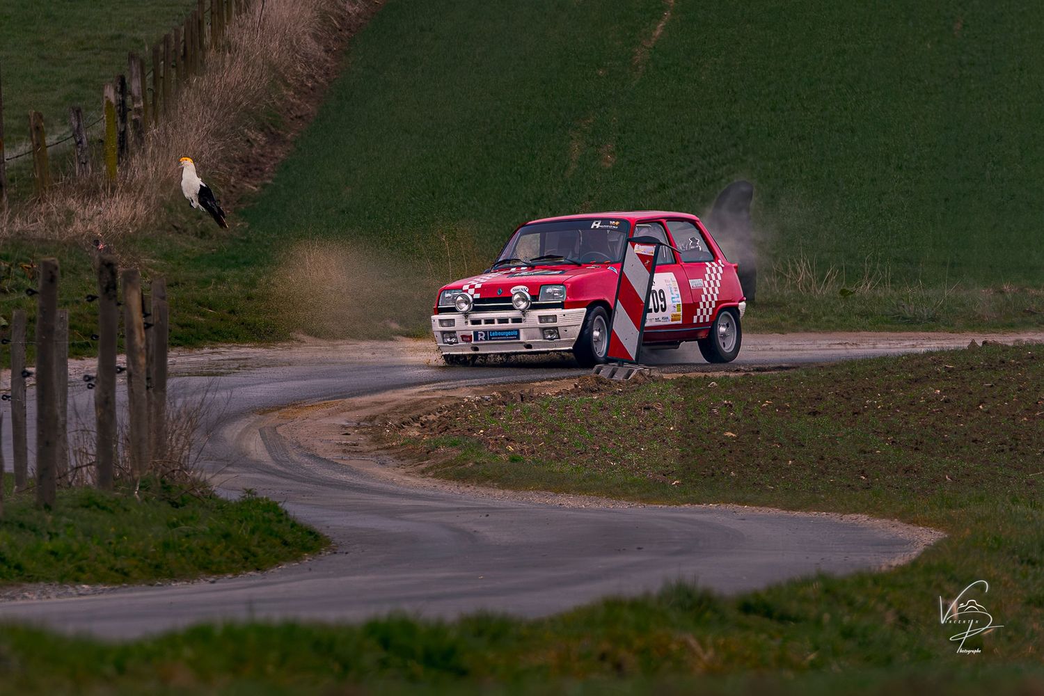 Rally car navigates a winding forest road during a racing competition.