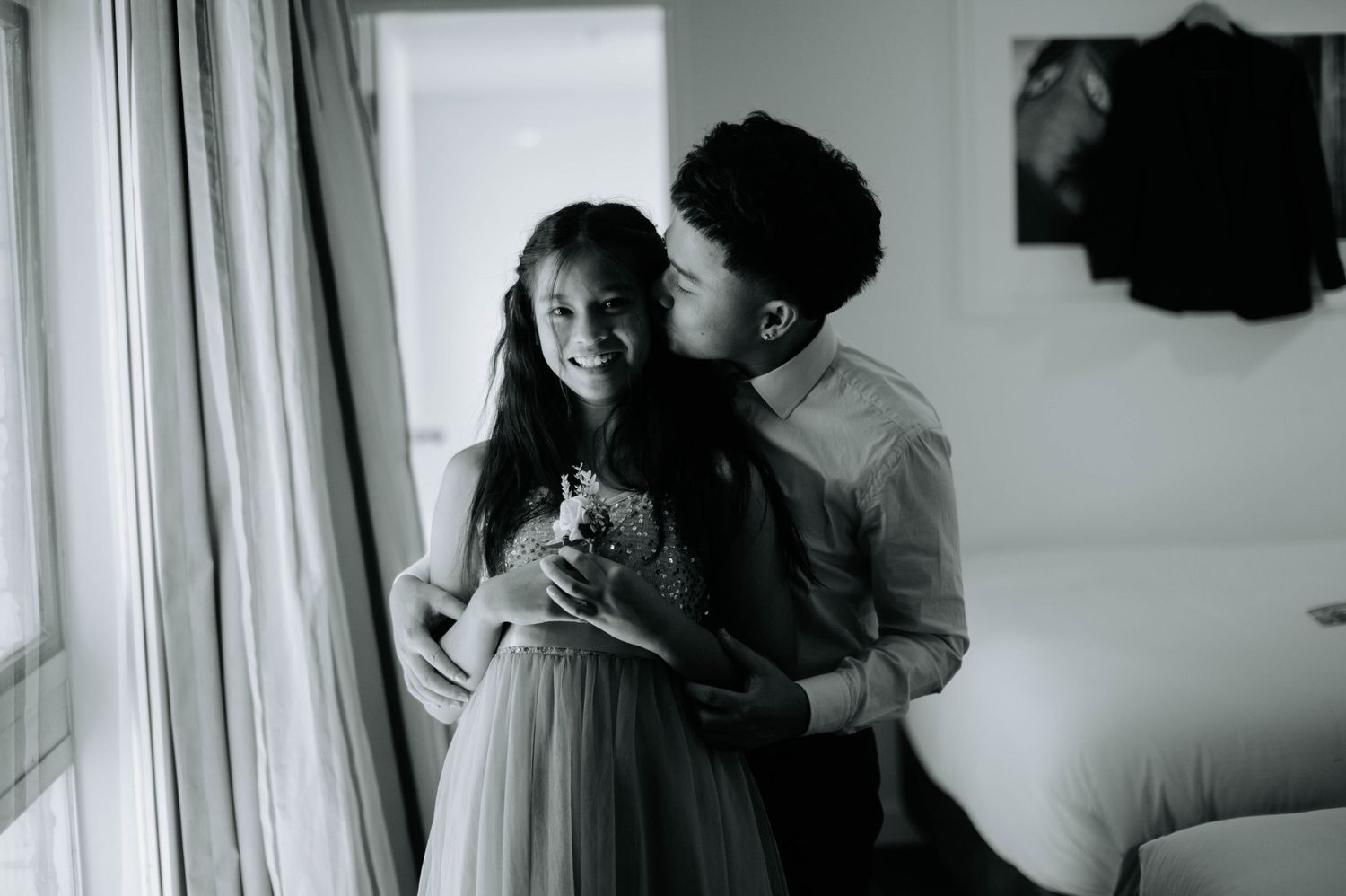 A tender moment captured in black and white by a bright window.
