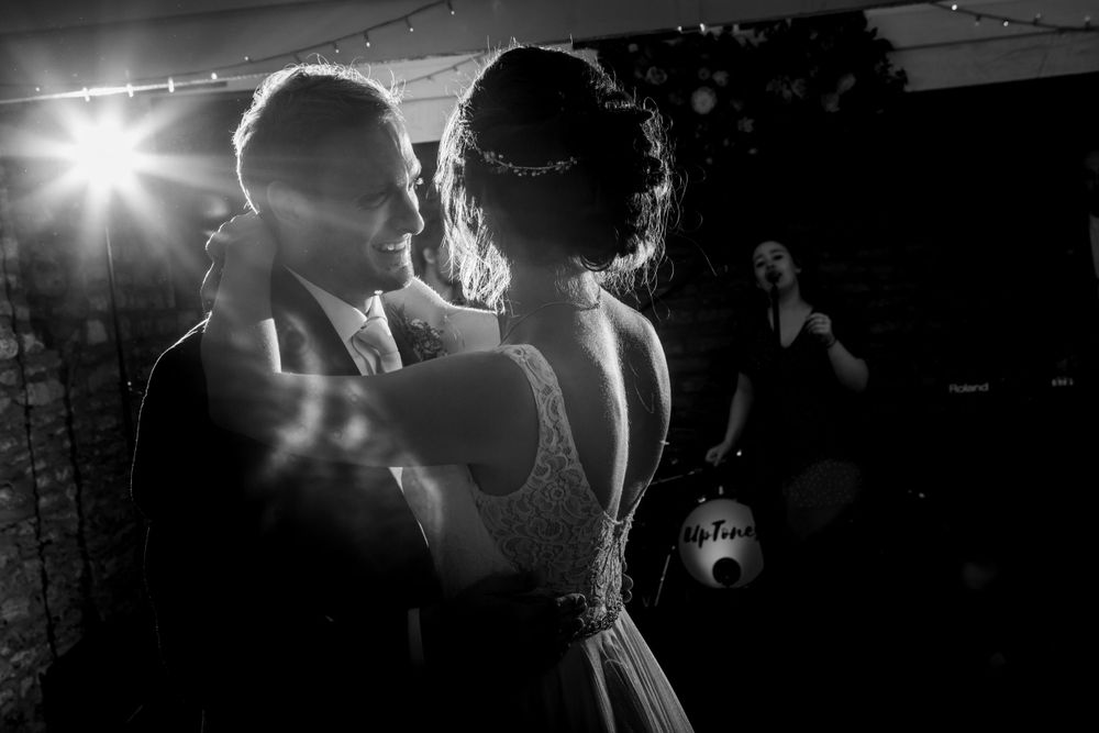 A couple shares their first dance at a wedding reception with a sunburst light effect in black and white photography.