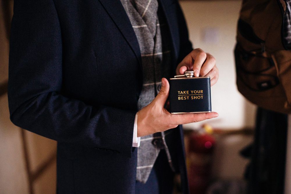 Close-up view of hands holding a small black book with gold text writing against a navy suit jacket.