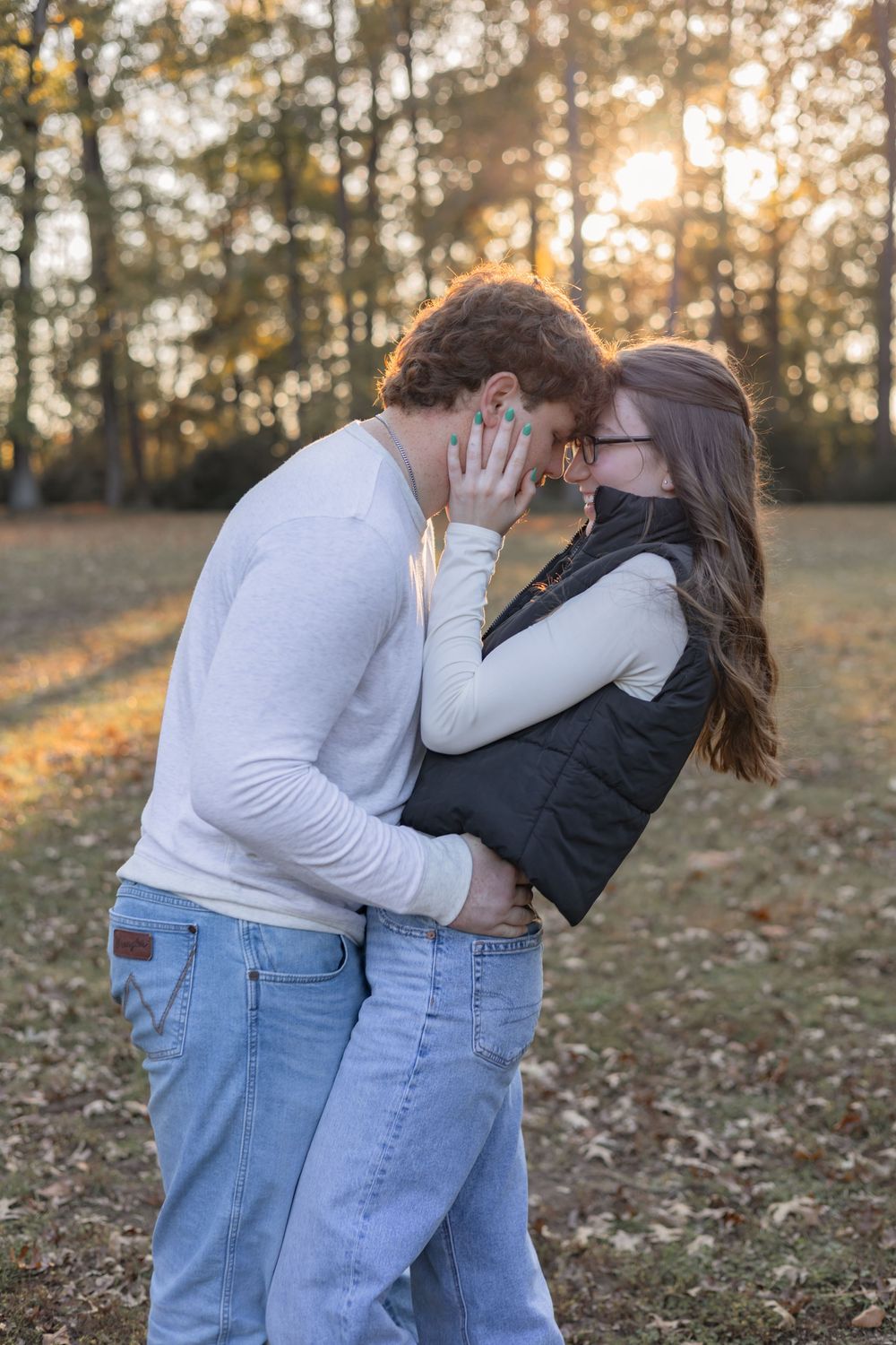 A romantic couple shares tender moments in a sunlit forest during golden hour.