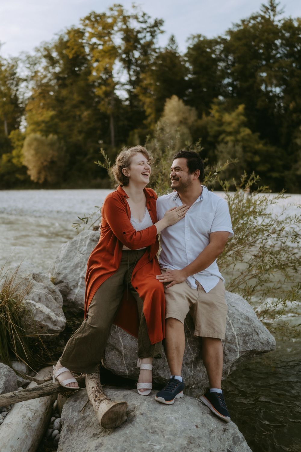 Frau und Mann sitzen auf einem Felsen vor einem Fluss