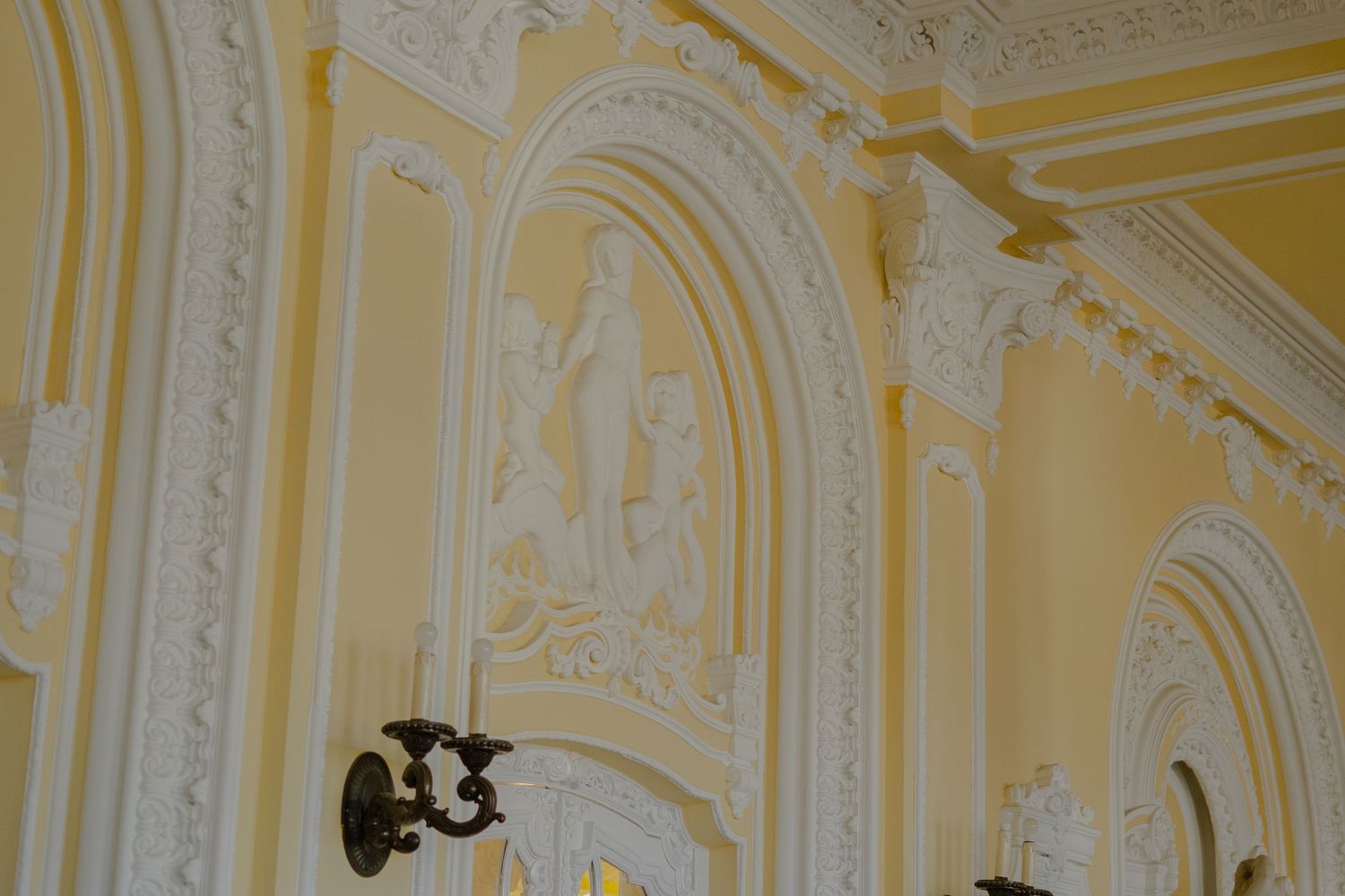 Ornate yellow and white architectural details with arched wall decorations and intricate moldings in a classical style.