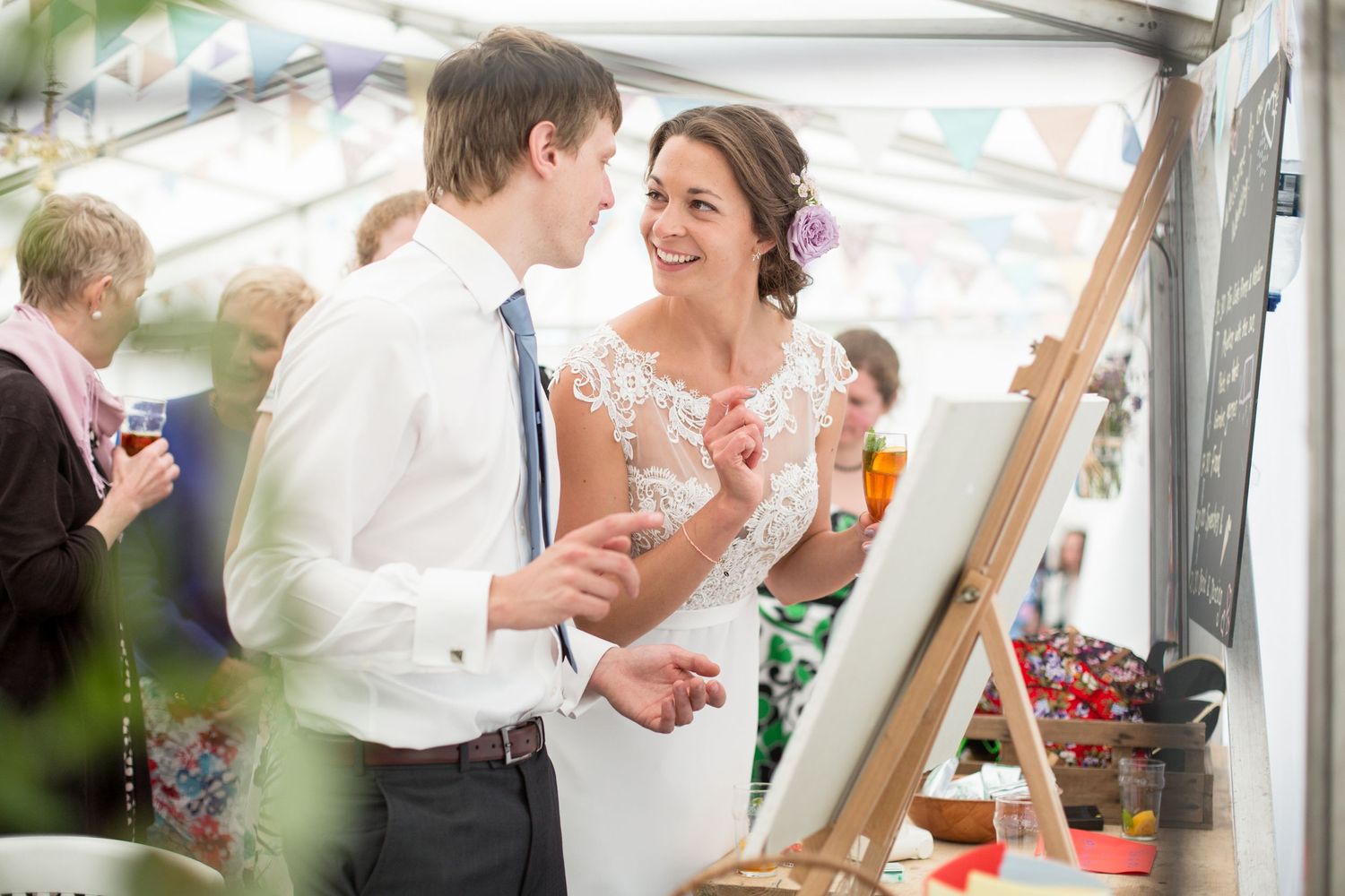 A sweet moment shared during a wedding reception under a tent with decorative lighting.