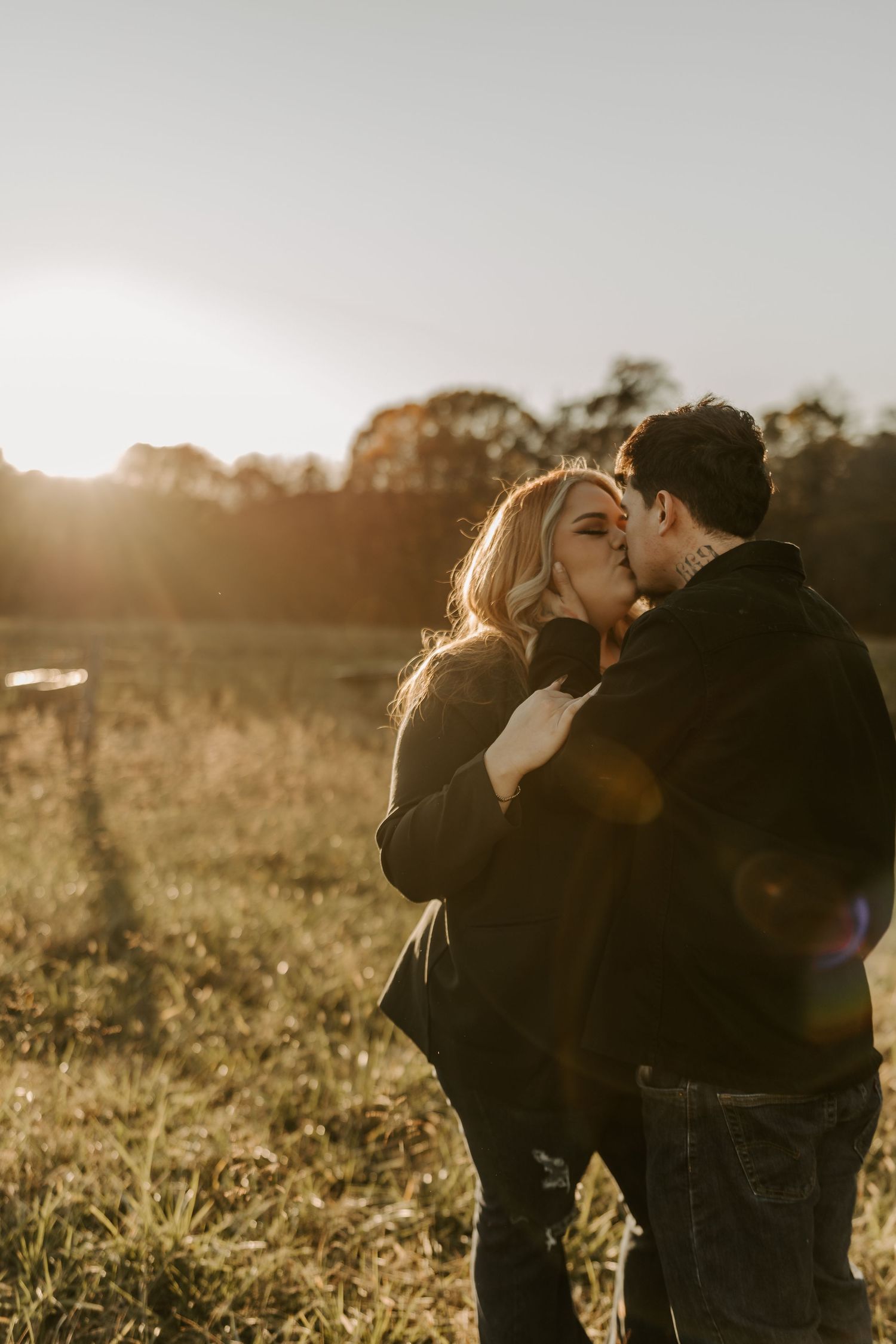 Romantic couple embracing in a sunlit field during golden hour.