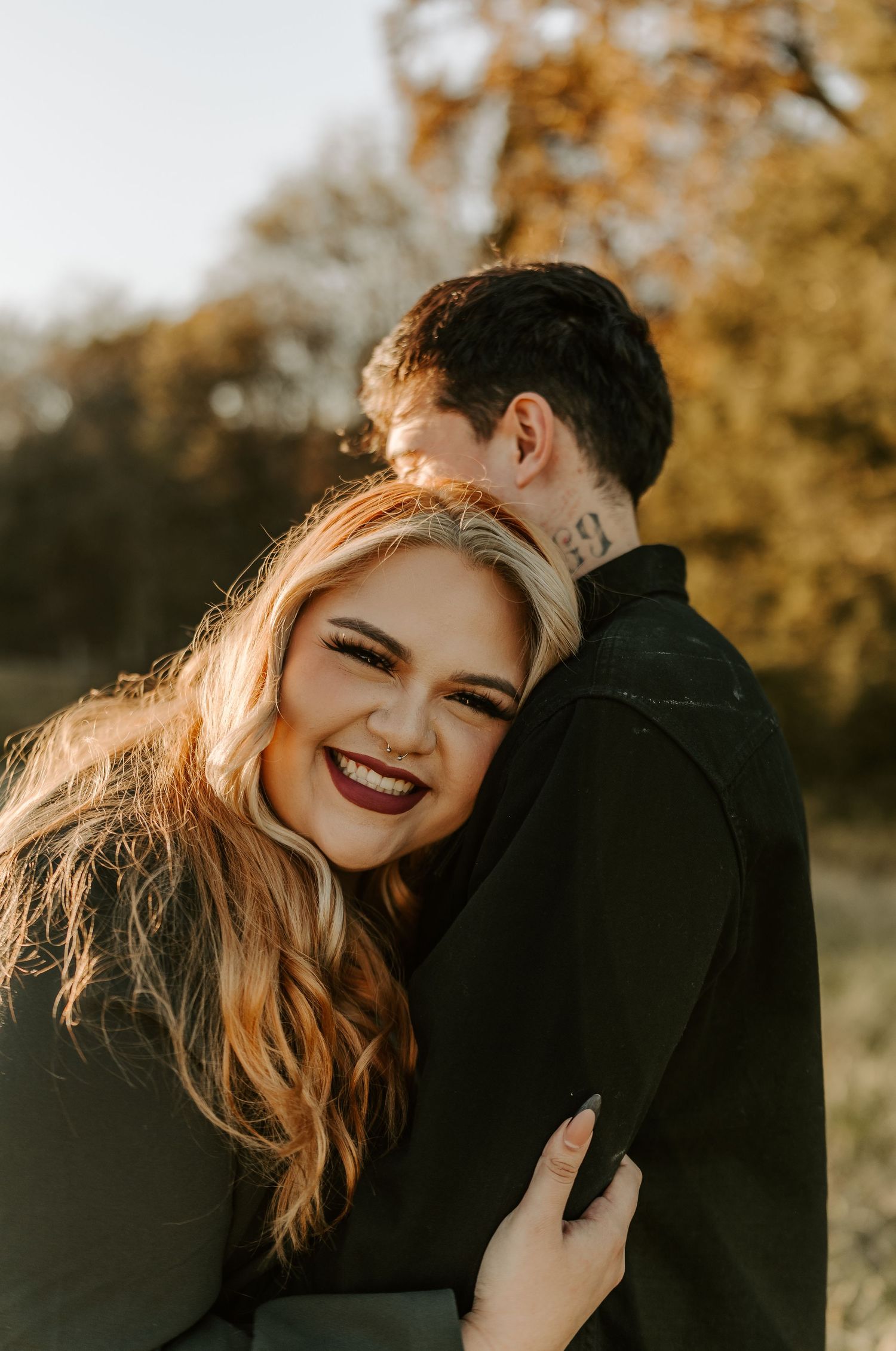 Intimate couple portrait with golden sunlight and autumn colors in background.