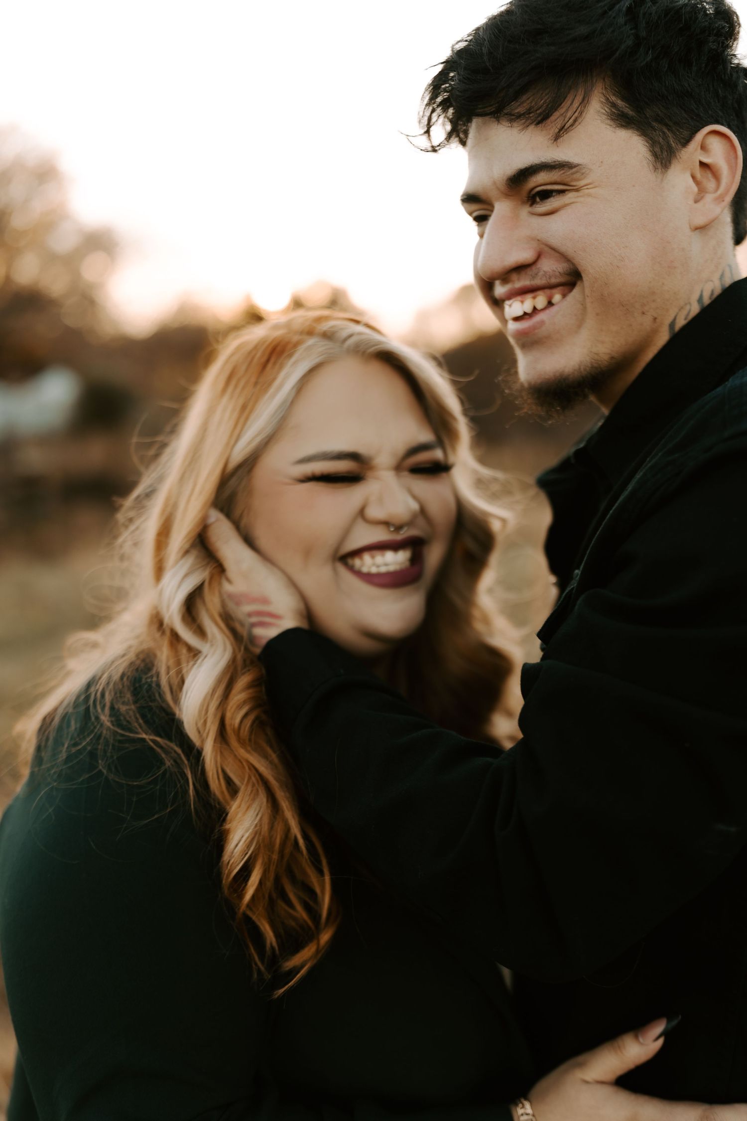Couple laughing together during outdoor sunset photo session.