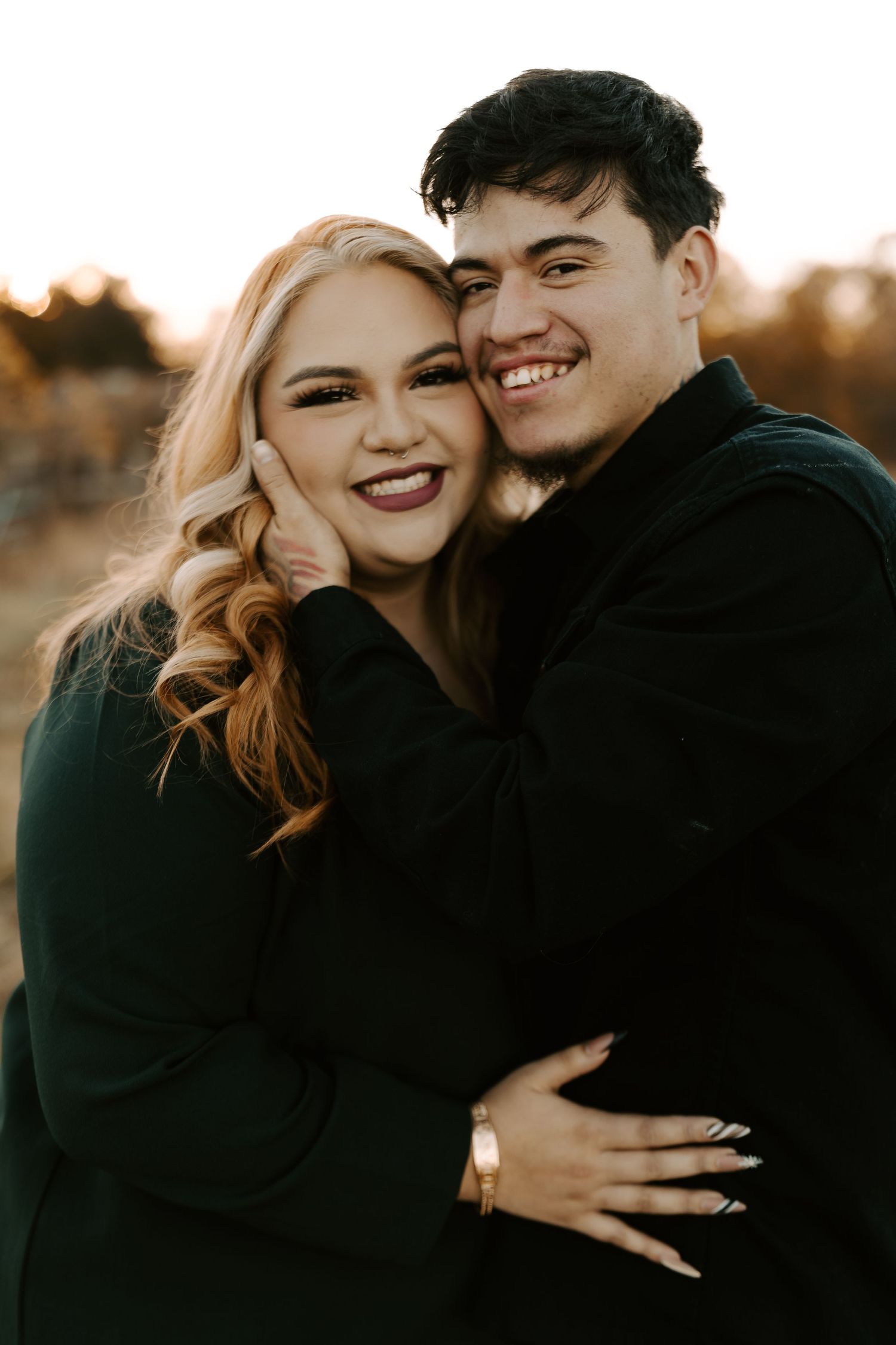 Happy couple in black sweaters sharing joyful moments outdoors.