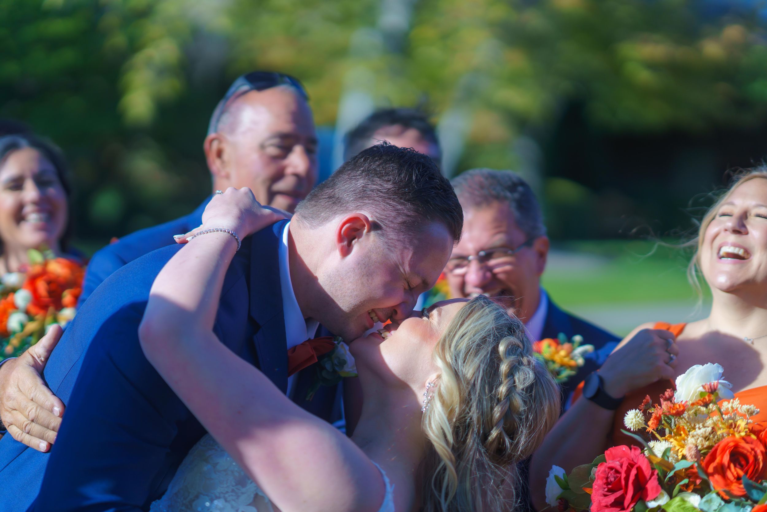 Wedding guests in navy blue attire gather outdoors during an autumn ceremony.