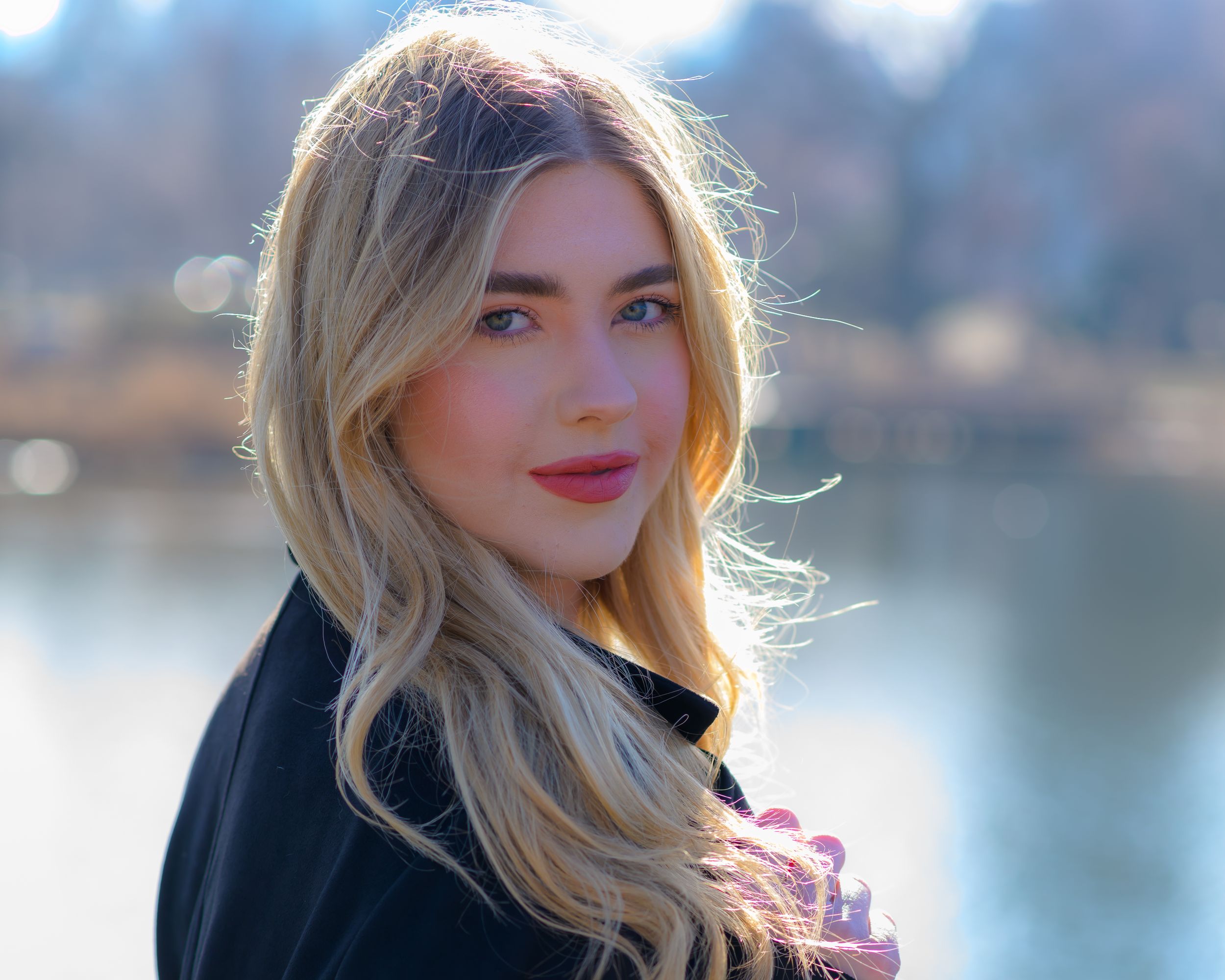 Outdoor fashion portrait with soft lighting and water backdrop.