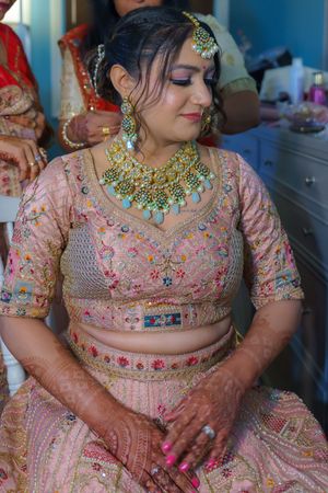 Traditional Indian bridal attire with intricate pink lehenga and ornate turquoise jewelry.
