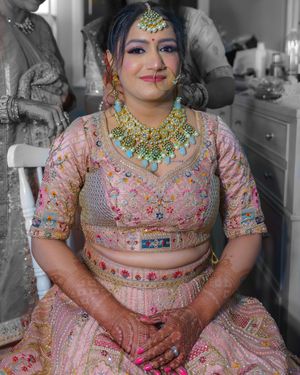 Detailed shot of bride in embellished pink lehenga with traditional Indian jewelry.