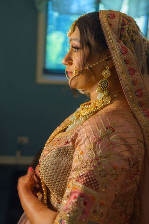 Close-up profile of Indian bridal attire showing detailed embroidery and jewelry.