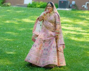 Pink floral lehenga outfit displayed in outdoor garden setting with lush green grass.