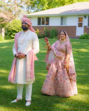Traditional Indian wedding attire in pink and white photographed on a sunny lawn.