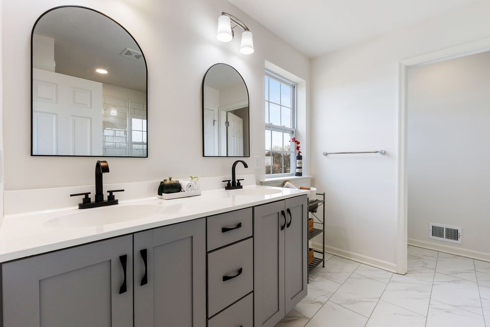 Modern bathroom interior with gray vanity cabinets, white countertops, and dual sinks in a bright, airy space.