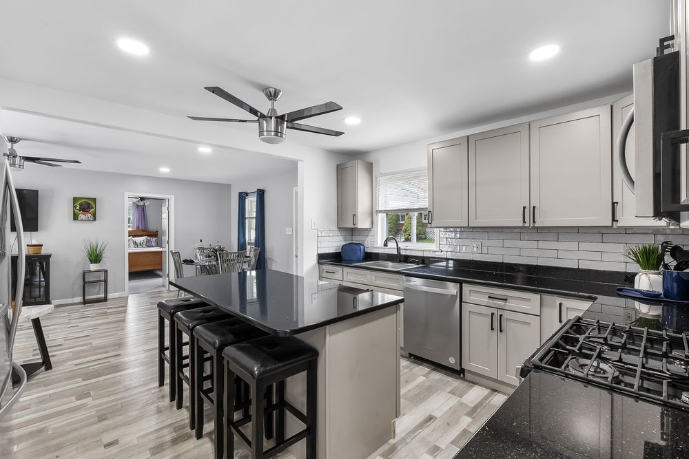 Modern kitchen interior with sleek white cabinets, stainless steel appliances, and dark countertops.