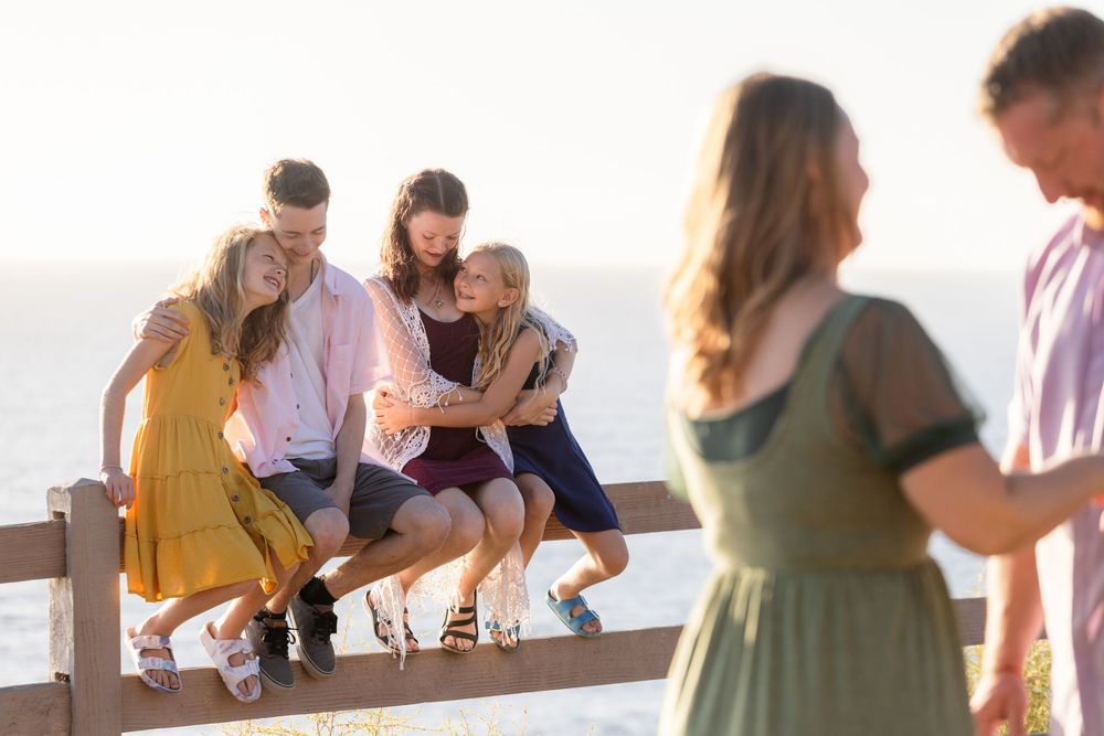 Group of friends sharing food and drinks while gathered around a rustic wooden table during an outdoor social gathering.