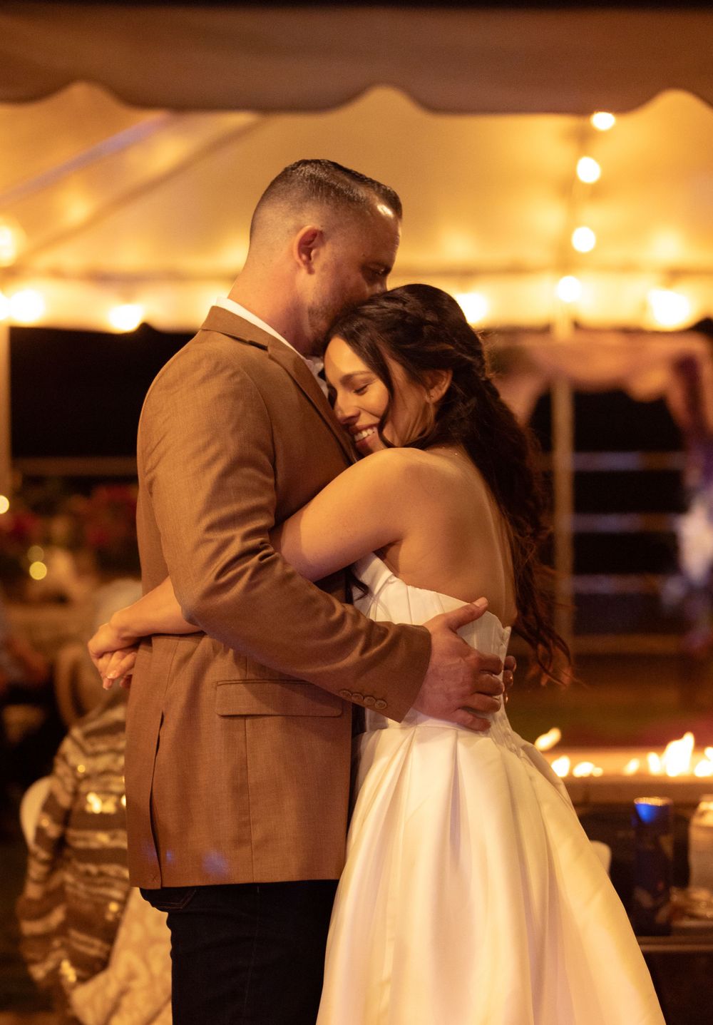 Couple dancing together at an evening wedding reception under warm lighting.