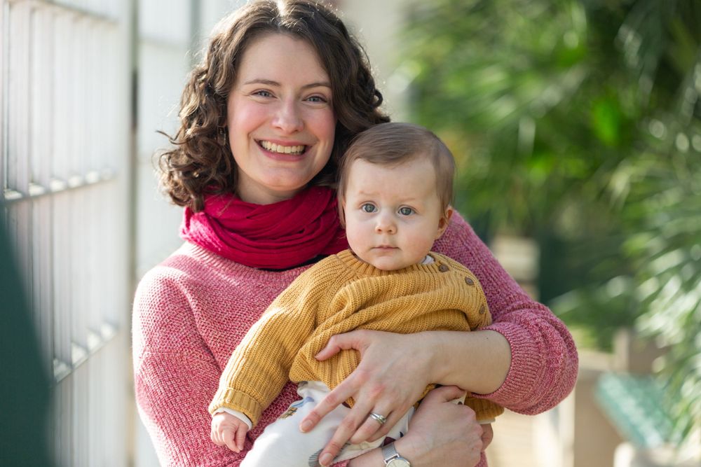 A warm winter moment as parent and baby in cozy sweaters share joyful connection.