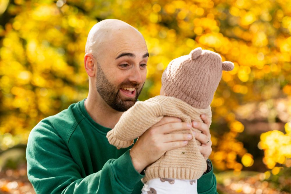 A couple in fall foliage shares a romantic moment while wearing cozy sweaters during an autumn photo session.