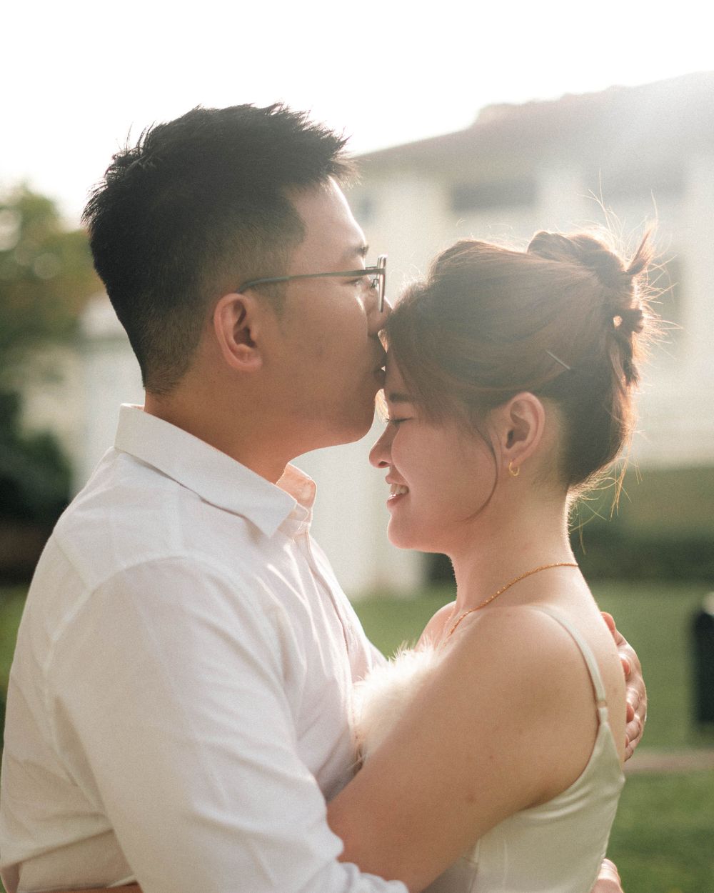 Romantic sunset portrait of couple in wedding attire embracing outdoors.