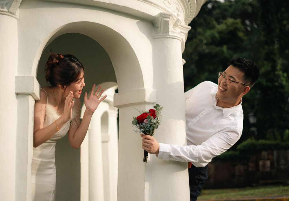 Playful wedding photo with couple on opposite sides of white stone gazebo.