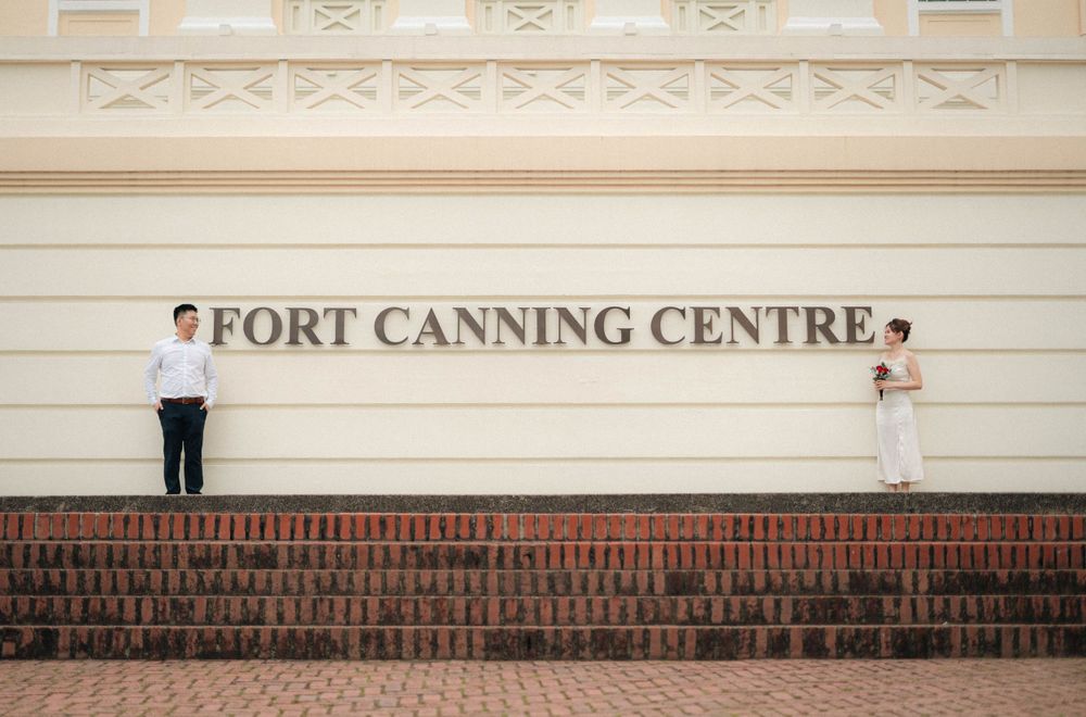 Couple posing creatively at opposite ends of Fort Canning Centre sign.