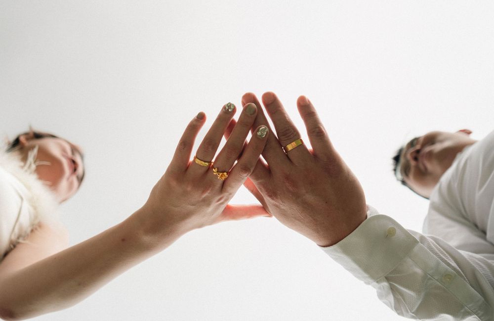 Two hands reaching out to touch each other against a bright white background.