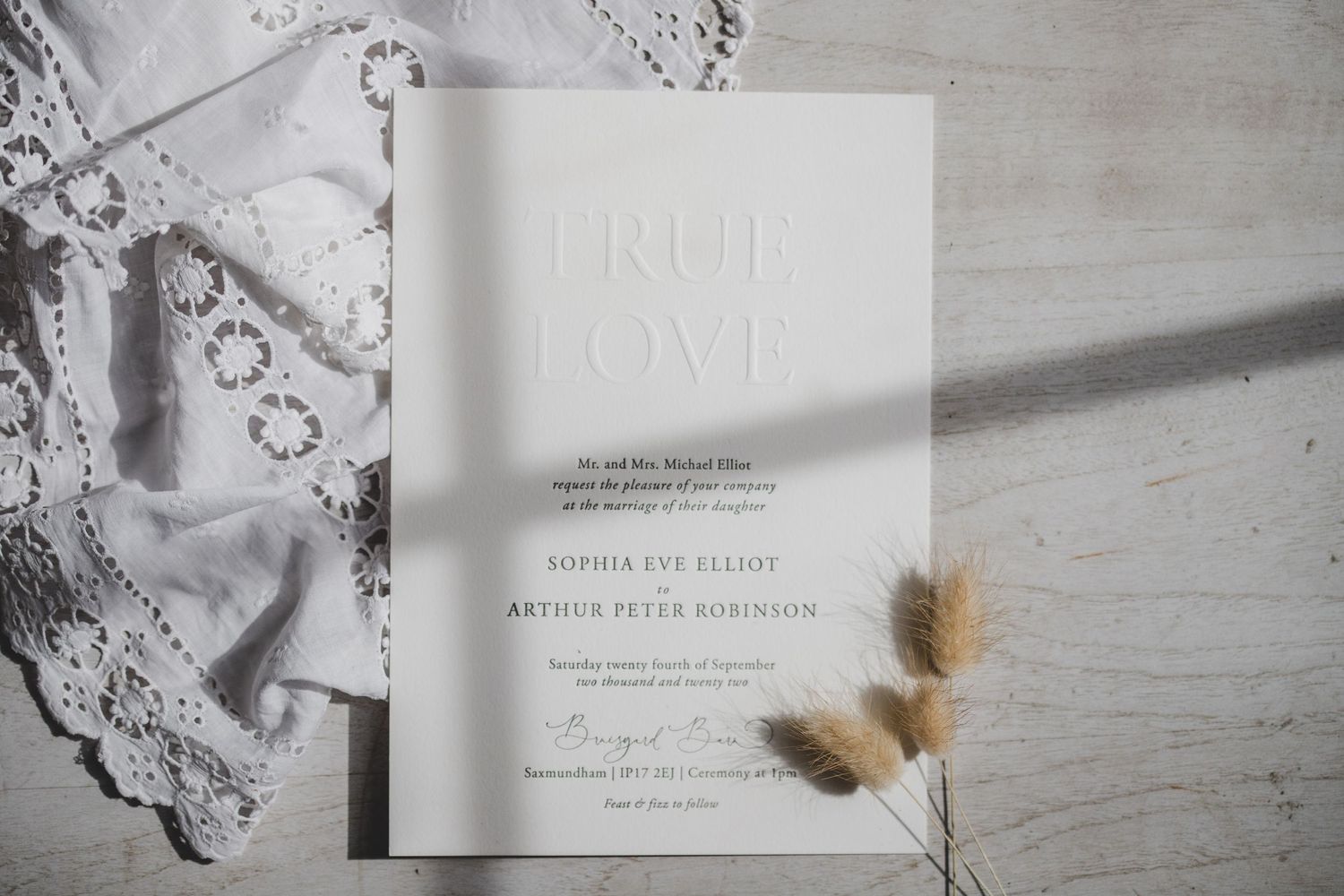 Elegant white wedding invitation with dried flowers on a textured surface.
Small Business product photography