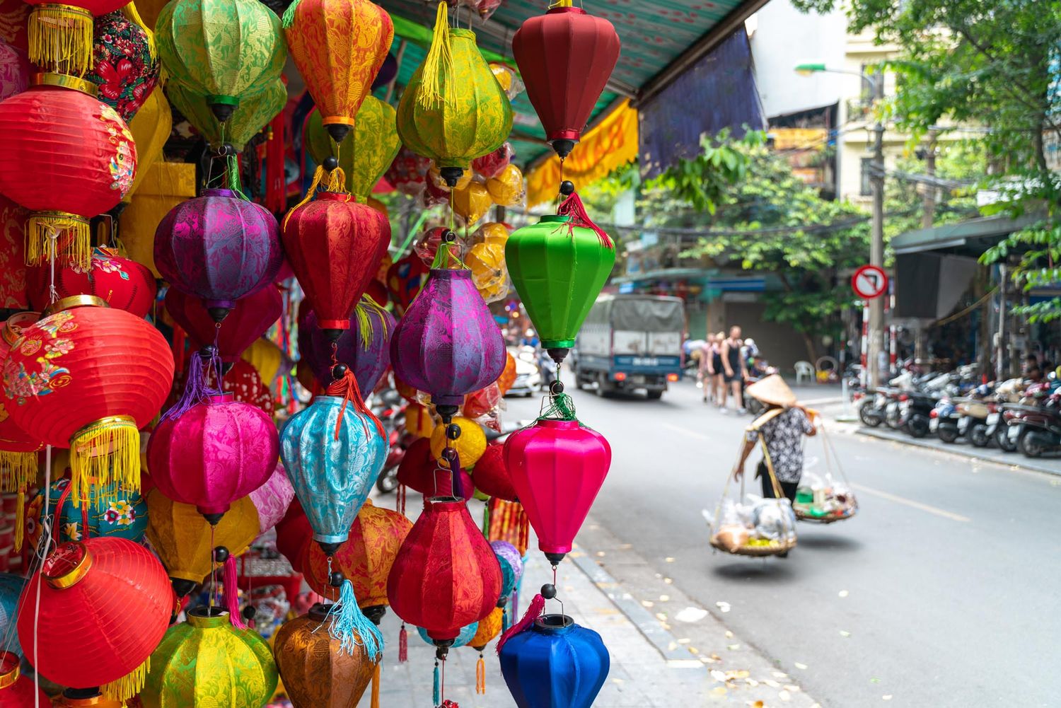 Colorful traditional Vietnamese silk lanterns hanging in Hoi An with street scene in background.