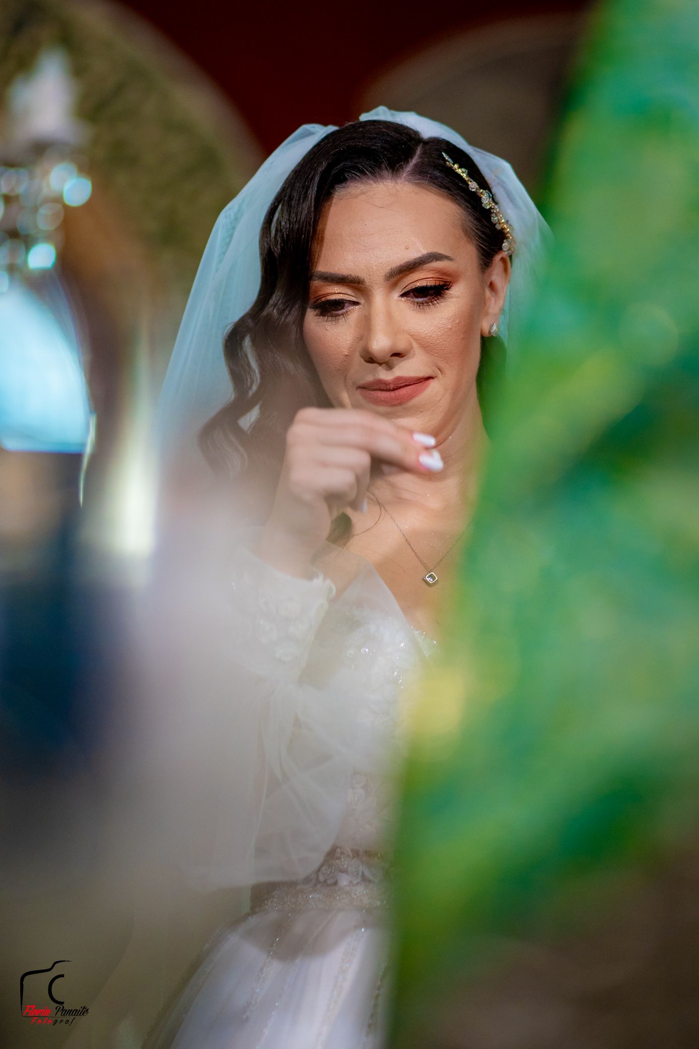 Candid moment of bride with flowing veil and curled hair smiling during wedding ceremony.